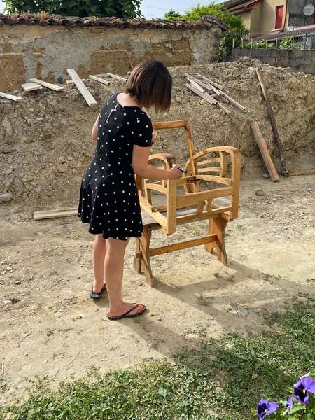 Delphine en train de teinter le bois brut du fauteuil Charleston en chêne clair